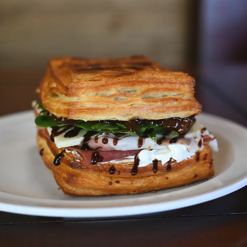 A Picnic Sandwich on a croissant, halved on a plate.