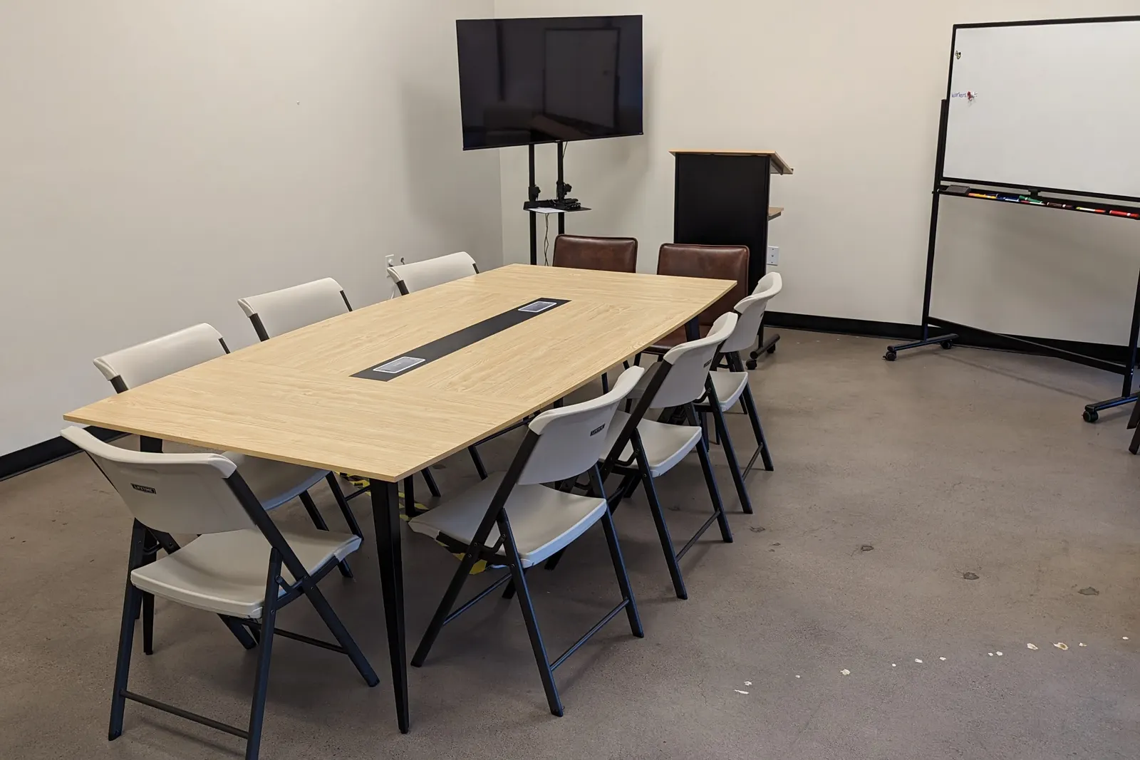 The conference room: a long table with power built into it, a screen on a rolling stand, and a mobile whiteboard.