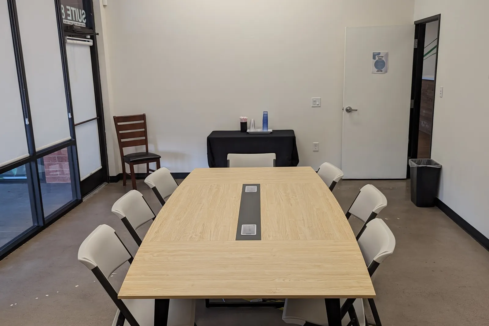 The conference room from the other end, with leather chairs at the head of the table and blinds on the window.