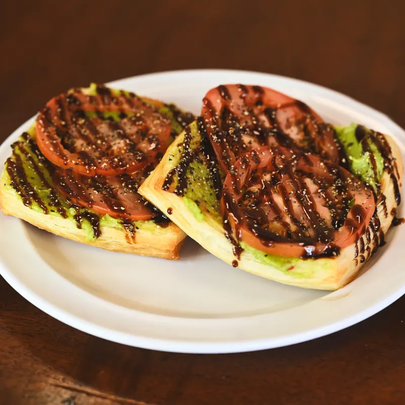 Two halves of the Avocado Croissant, with tomato and balsamic glaze.