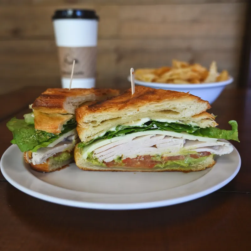 The Boring Sandwich, halved on a plate with sea salt chips and a coffee.
