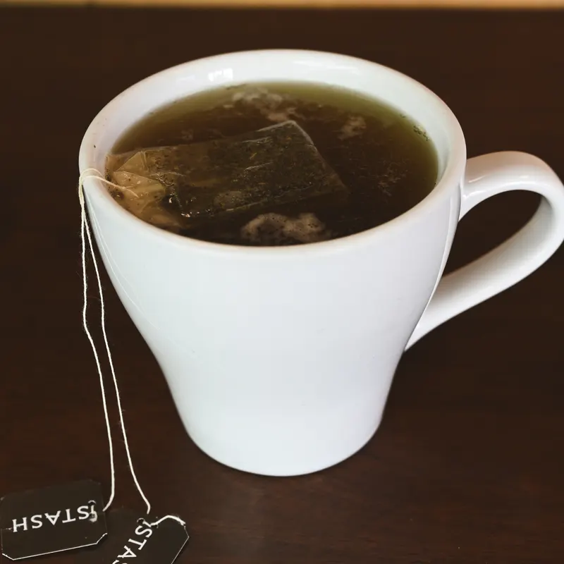 A cup of tea steeping, the tag hanging over the side.