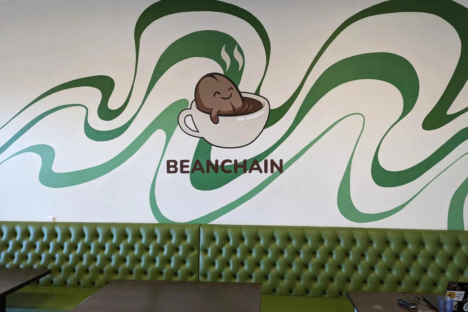 Inside the shop: the green ribbon mural above the banquette seating.
