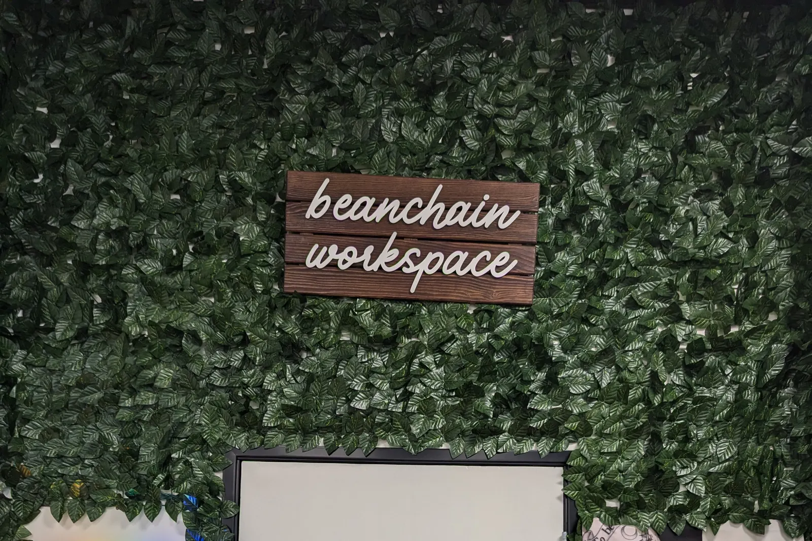 The workspace door, framed by a wall of green foliage with a hand-lettered beanchain workspace sign.